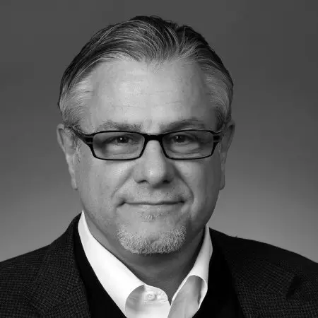 A man with glasses and a beard wearing a suit.